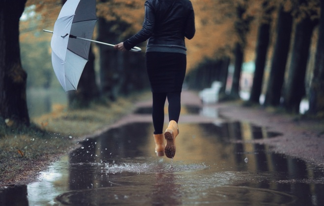 Frau mit Regenschirm in einer Pfütze