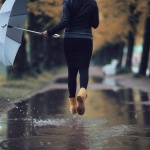 Frau mit Regenschirm in einer Pfütze